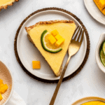 Slice of mango tart topped with lime slice on marble background
