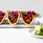 Two sweet potato tofu tacos topped with red cabbage slaw and fresh cilantro
