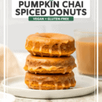 stack of pumpkin chai donuts on white plate with cup of chai in the background