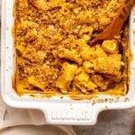 No-Boil Vegan Pumpkin Mac & Cheese in white casserole dish, on marble counter surrounded by pumpkins and rosemary