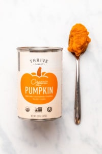 Can of Thrive Market pumpkin puree next to spoon with puree on it