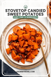 Plate of glazed sweet potatoes and pecans on marble background with navy linen and gold fork