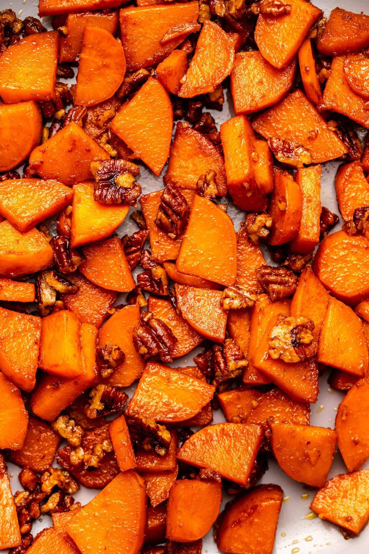 Overhead photo of candied sweet potatoes and pecans in grey pan 