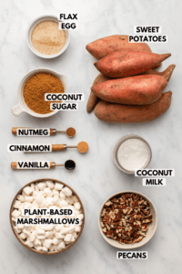 Ingredients for vegan sweet potato casserole in small white bowls on marble background. Clockwise text labels read sweet potatoes, coconut milk, pecans, plant-based marshmallows, vanilla, cinnamon, nutmeg, coconut sugar, and flax egg