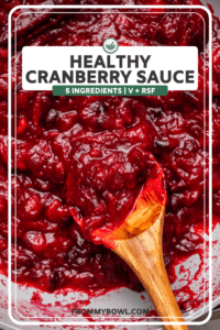 Cooked cranberry sauce in sauté pan with a wooden spoon