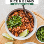 Two bowls of rice and beans topped with cilantro, with lime wedges on the side.