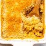 Baked Vegan Mac & Cheese topped with golden breadcrumbs in white casserole dish with wooden spoon