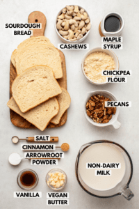 Ingredients for baked french toast casserole on stone countertop. Clockwise text labels read cashews, maple syrup, chickpea flour, pecans, non-dairy milk, vegan butter, vanilla, arrowroot powder, cinnamon, salt, and sourdough bread