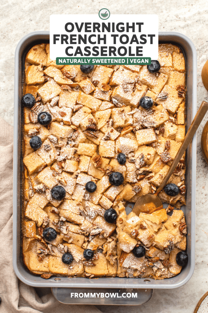 vegan french toast casserole in serving dish topped with powdered sugar and blueberries