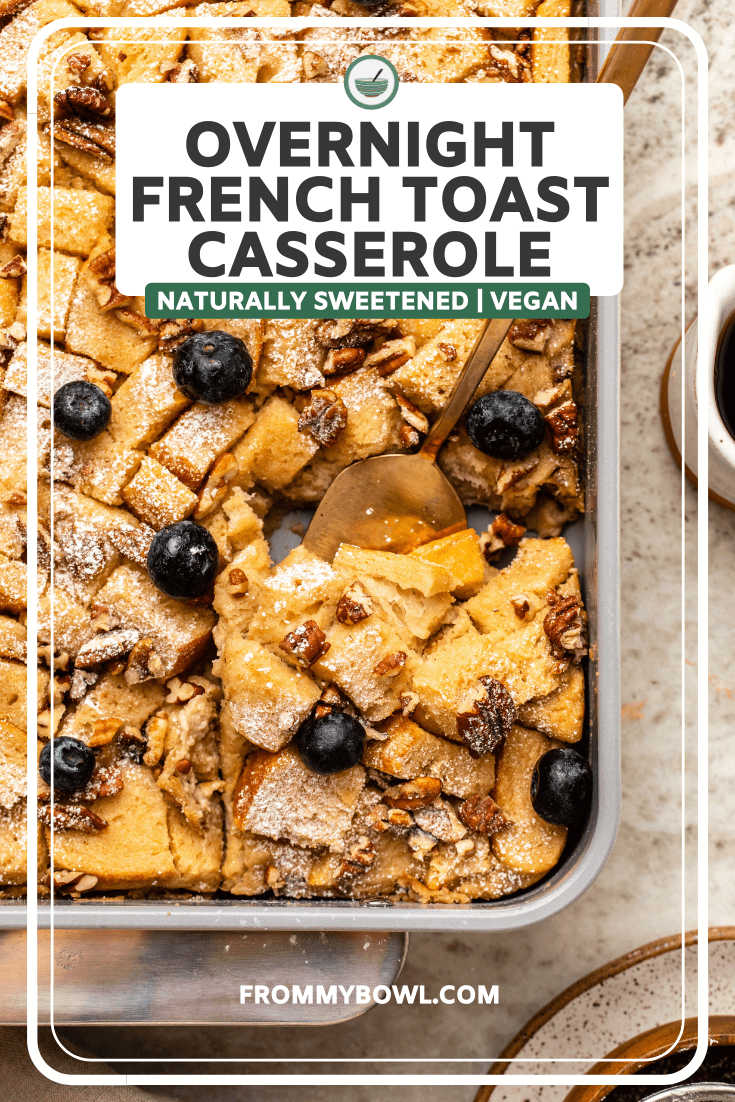Sliced french toast casserole in baking dish topped with powdered sugar and blueberries