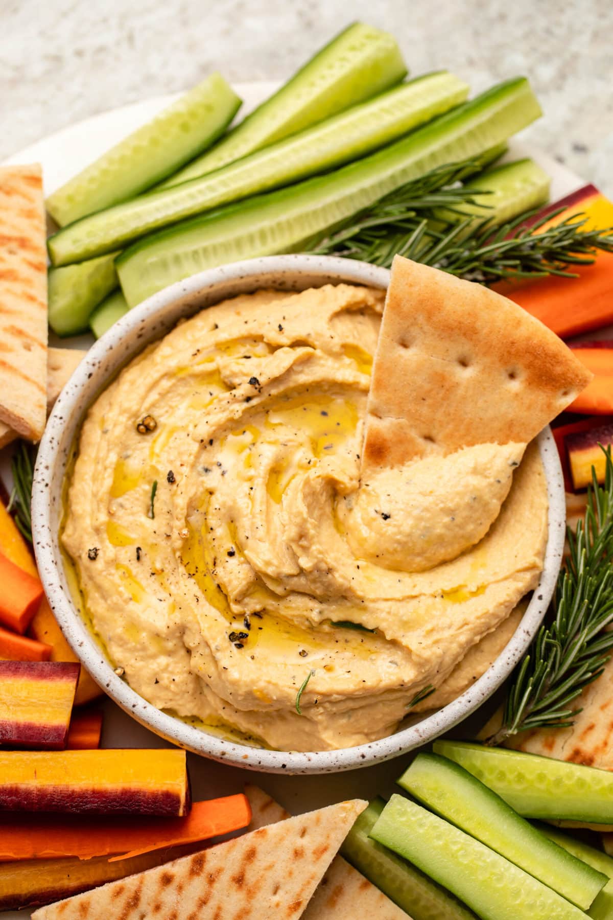Butternut squash hummus on vegetable tray with slice of pita dipping into hummus