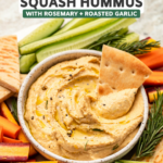 Butternut squash hummus on vegetable tray with slice of pita dipping into hummus