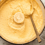 Blended butternut squash in food processor with gold spoon