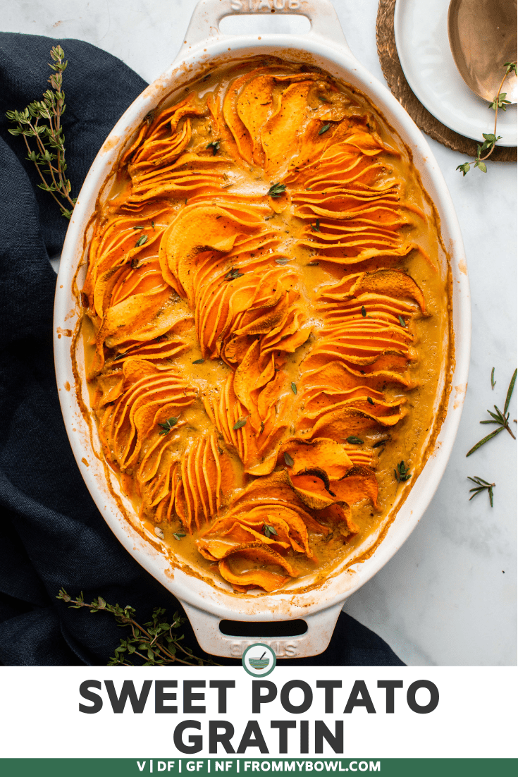 Sweet potato gratin topped with fresh thyme in baking dish with navy linen and gold serving spoon