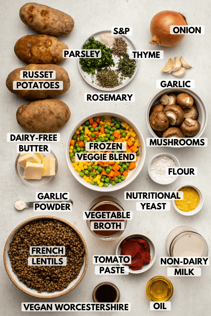 Ingredients for shepherd's pie on marble background. top-to-bottom text labels read russet potato, parsley, salt & pepper, thyme, onion, rosemary, garlic, dairy-free butter, frozen vegetable blend, mushroom, garlic powder, vegetable broth, nutritional yeast, french lentils, tomato paste, non-dairy milk, vegan Worcestershire, and oil