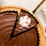 No-Bake Chocolate Peppermint Tart with slice cut and topped with whipped cream and candy cane pieces