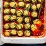 Zucchini Lasagna Roll-Ups in baking dish with tomato sauce and topped with fresh basil