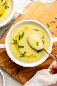 Bowl of potato leek soup with golden spoon taking a scoop of soup