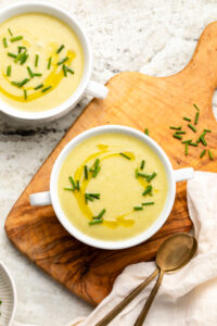 Two bowls of potato leek soup topped with olive oil and chives