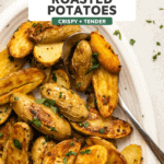 roasted potatoes topped with parsley on white serving dish on kitchen countertop