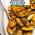 roasted potatoes topped with parsley on white serving dish on kitchen countertop