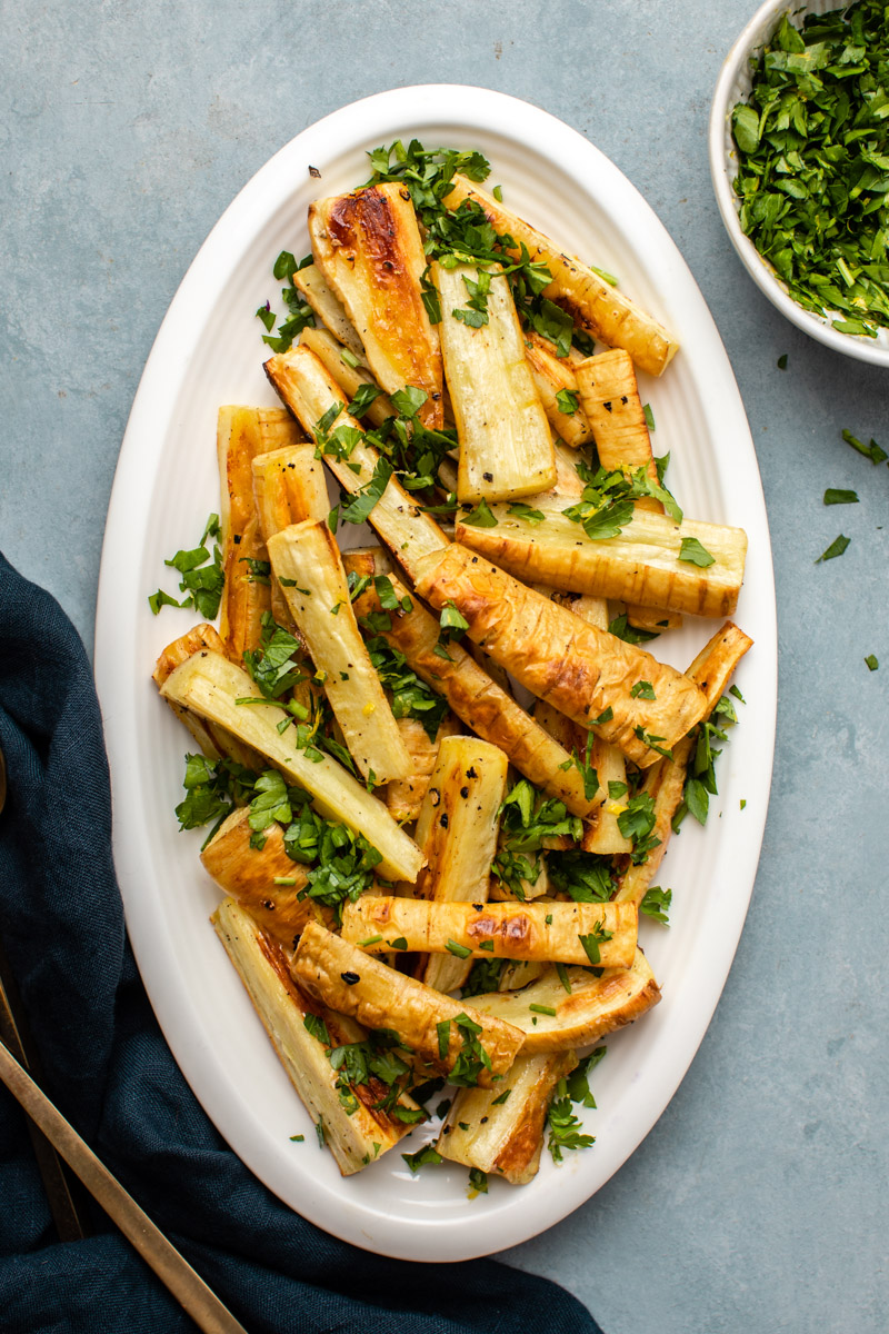 roasted parsnips on oval white plate topped with gremolata