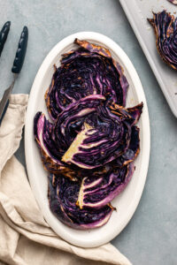 Roasted red cabbage wedges on serving plate on blue background