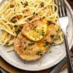 Vegan chicken piccata topped with lemon caper sauce and next to pasta on a plate