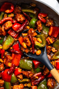 Kung Pao Tofu stir fry in sauté pan with wooden spoon