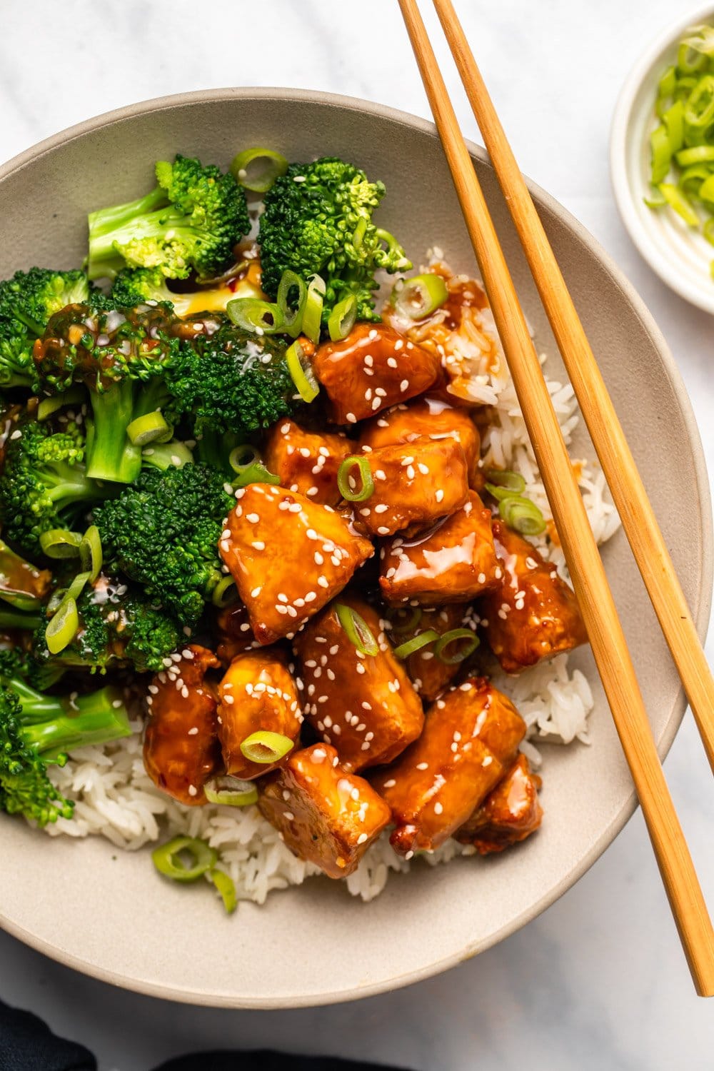 Orange tofu in bowl with white rice and broccoli