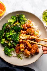 crispy orange tofu in bowl with broccoli and rice