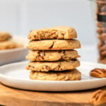 stack of pecan sandies on white plate with jar of pecans in the back