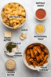 Ingredients for buffalo ranch pasta in small bowls on marble background