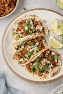 vegan tacos topped with onion and cilantro on white plate