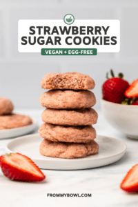 Stack of strawberry sugar cookies with bowl of strawberries in the background