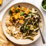 rice, roasted veggies, and tofu in bowl topped with tahini sauce