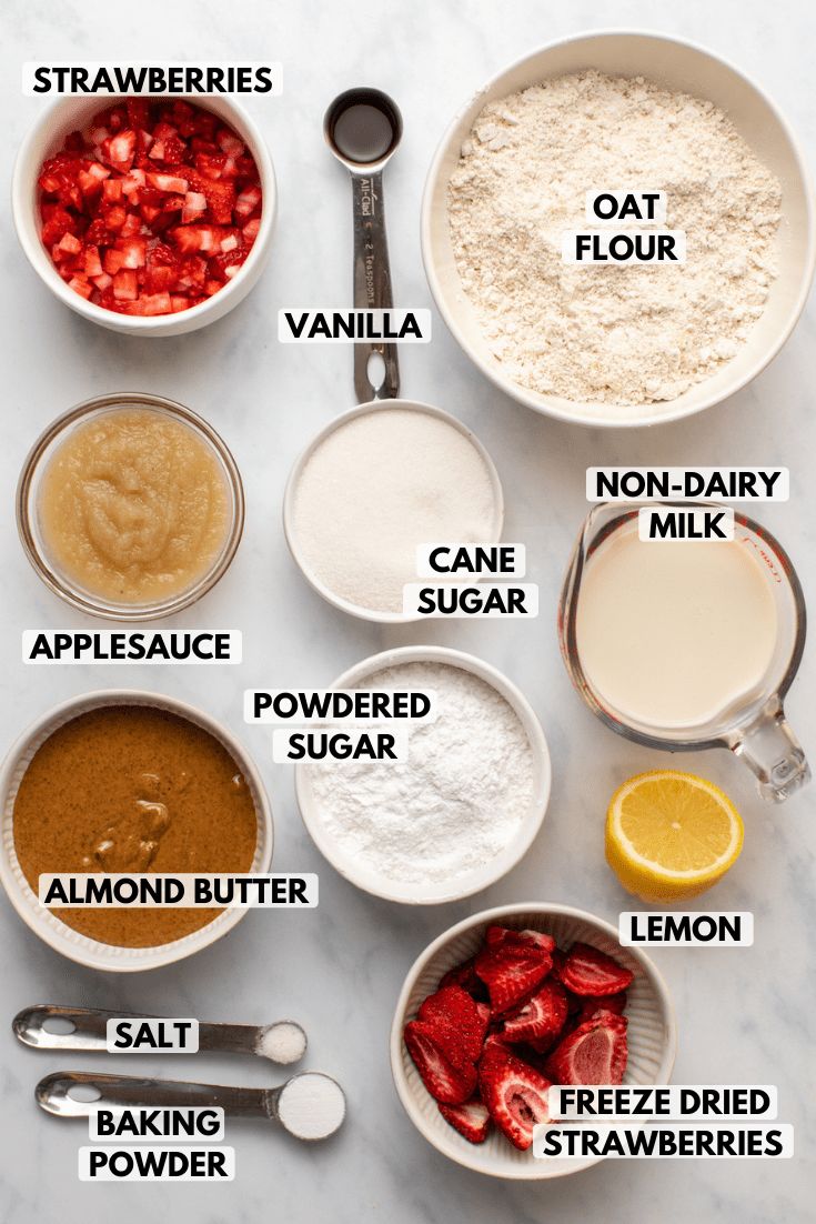 ingredients for strawberry donuts in small bowls on marble background
