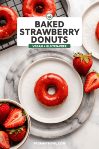 baked strawberry donut topped with strawberry glaze on white plate with fresh strawberries