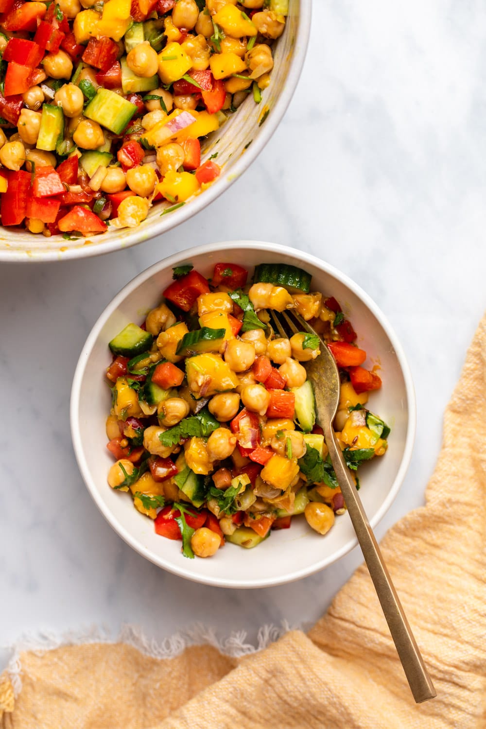 Mango and chickpea salad in white bowl on marble countertop