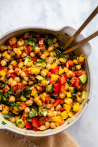 Mango Chickpea Salad in white serving bowl with gold tongs