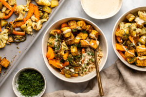 bowl of ranch tofu with roasted vegetables and rice topped with tahini sauce