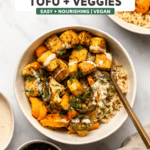white bowl with crispy tofu, roasted veggies, rice, and tahini sauce