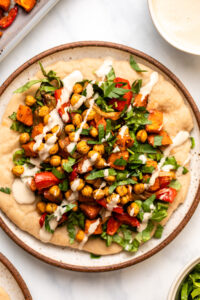 sheet pan chickpeas and vegetables on pita with lettuce and tahini sauce