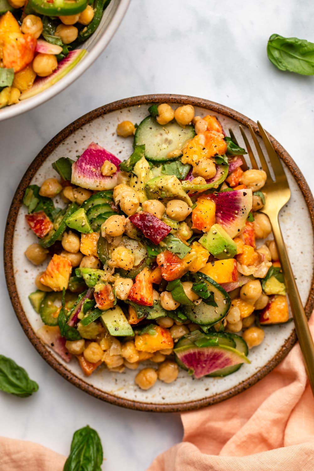peach and chickpea salad on plate with gold fork and fresh basil