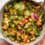 Spicy peach and chickpea salad in large bowl with golden tongs
