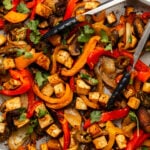 Roasted vegetables and tofu on sheet pan with lime wedges and cilantro