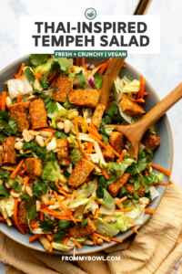 tempeh salad with peanuts, carrots, and cilantro in large bowl with wooden tongs