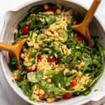Tomato Basil Orzo Salad in large serving bowl with wooden tongs