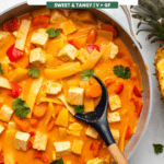 pineapple curry in large saute pan with wooden spoon