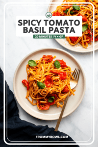spicy tomato basil pasta on two white plates with gold forks